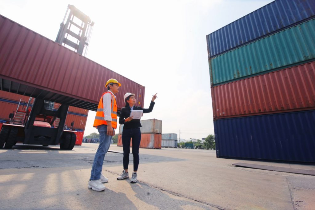 Comercializadora, dos encargados de aduanas revisando la mercancía almacenada en contenedores de un puerto